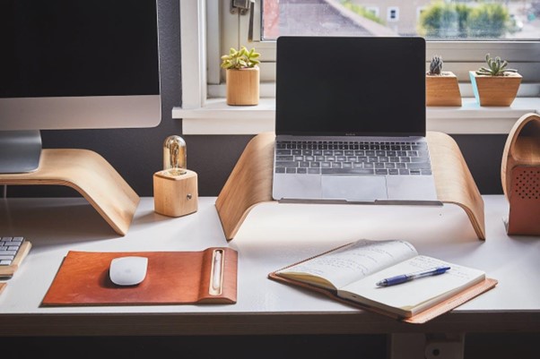 Laptop, mousepad, and notebook on a working desk.