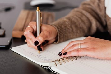 A woman writing down notes in a diary.